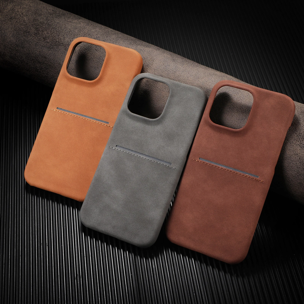 iPhone 16 Pro Max surrounded by premium leather cases in brown and black colors on a white desk